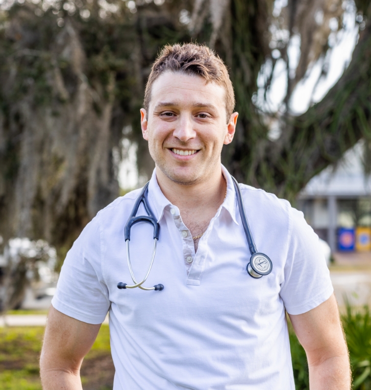 Orlando concierge pediatrician smiling outdoors in white polo shirt and stethoscope