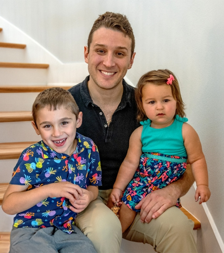 Doctor Weiss sitting at bottom of staircase with his wife and two children