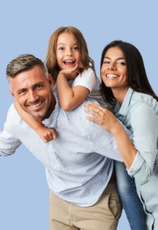 Family of three with the father giving the child a piggyback ride