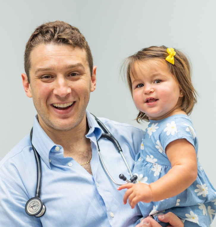 Orlando concierge pediatrician smiling and carrying a toddler girl