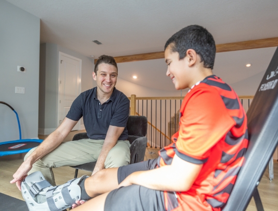 Doctor Weiss adjusting a leg cast on a young boy in his home