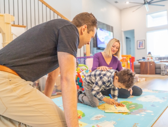 Young boy coloring on the floor while his mother and pediatrician watch