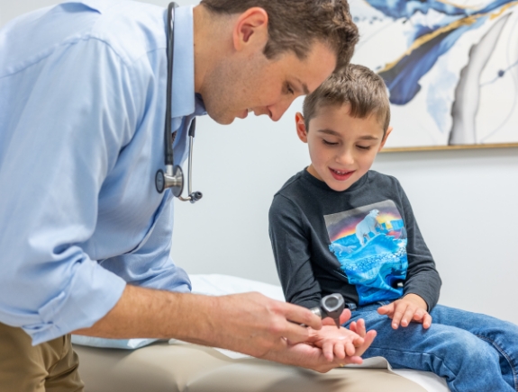 Doctor Weiss showing an otoscope to a young boy in treatment room